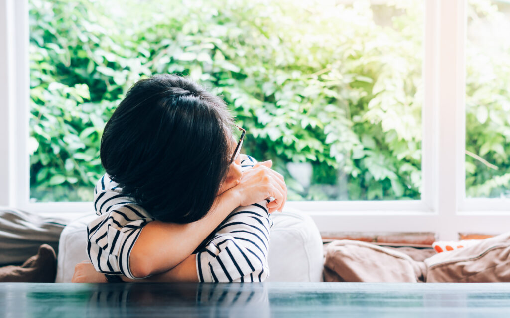 A woman at her kitchen table looking overwhelmed and anxious